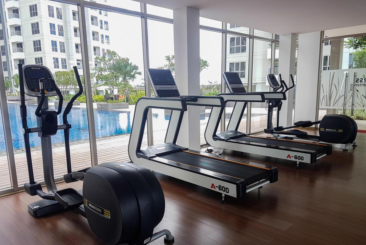 Gymnasium with treadmills facing the pool at M-Town Residence