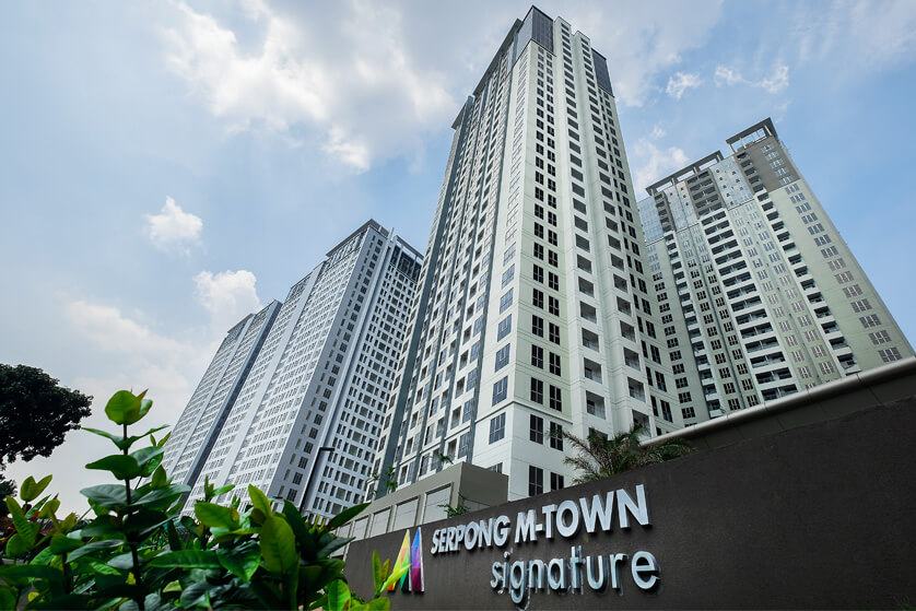 M-Town Residence apartment towers in Gading Serpong seen from below, with the entrance sign in the foreground