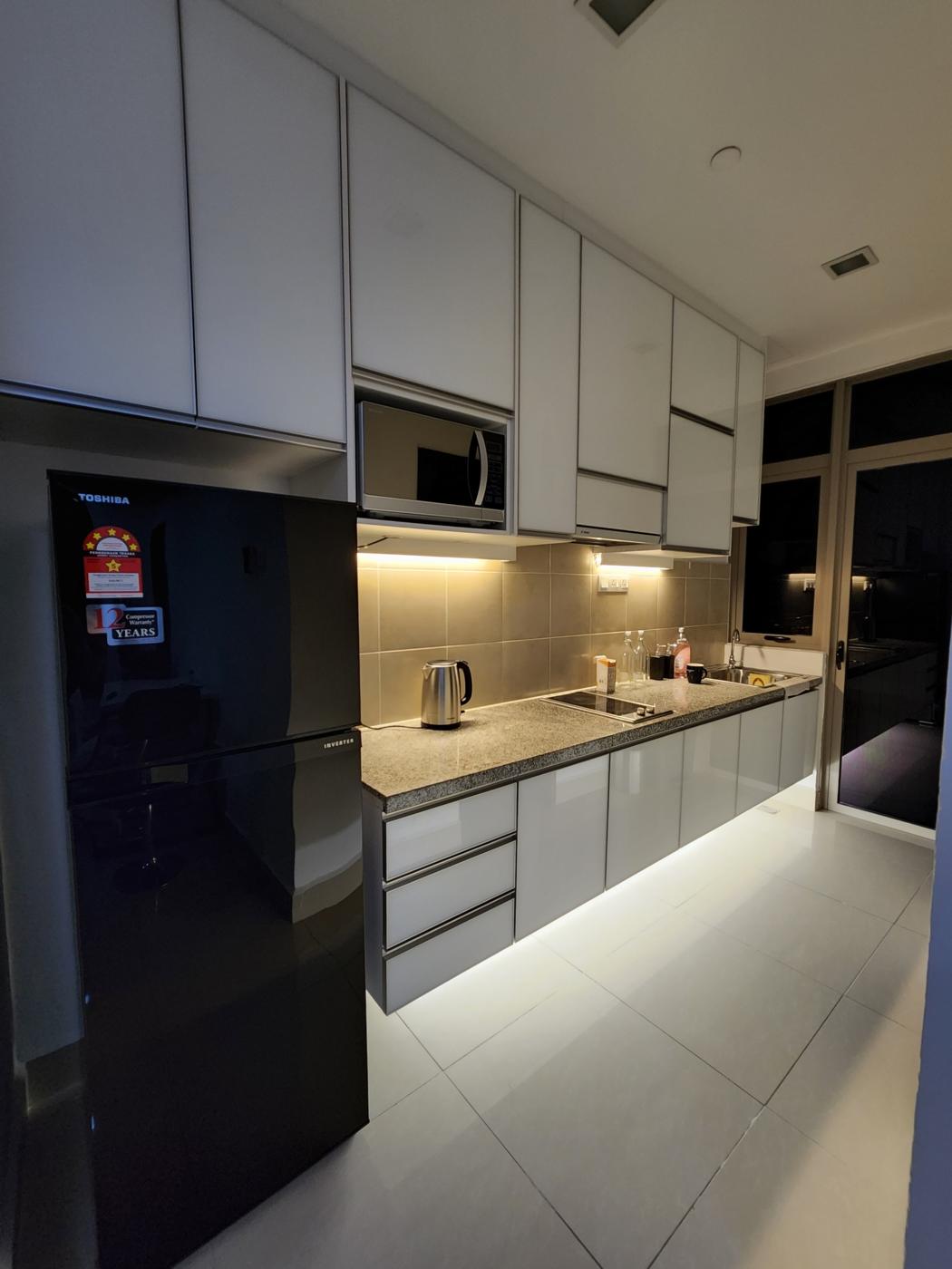 Kitchen with refrigerator, microwave, hob and under-cabinet lighting