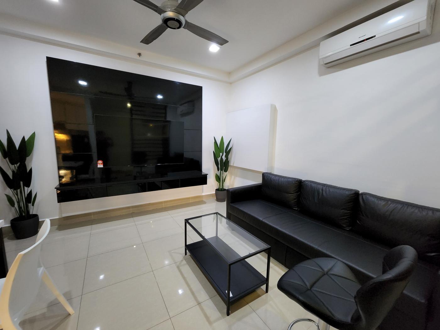 Furnished SOHO unit living area in Cyberjaya with leather sofa, glass coffee table and wall-mounted television