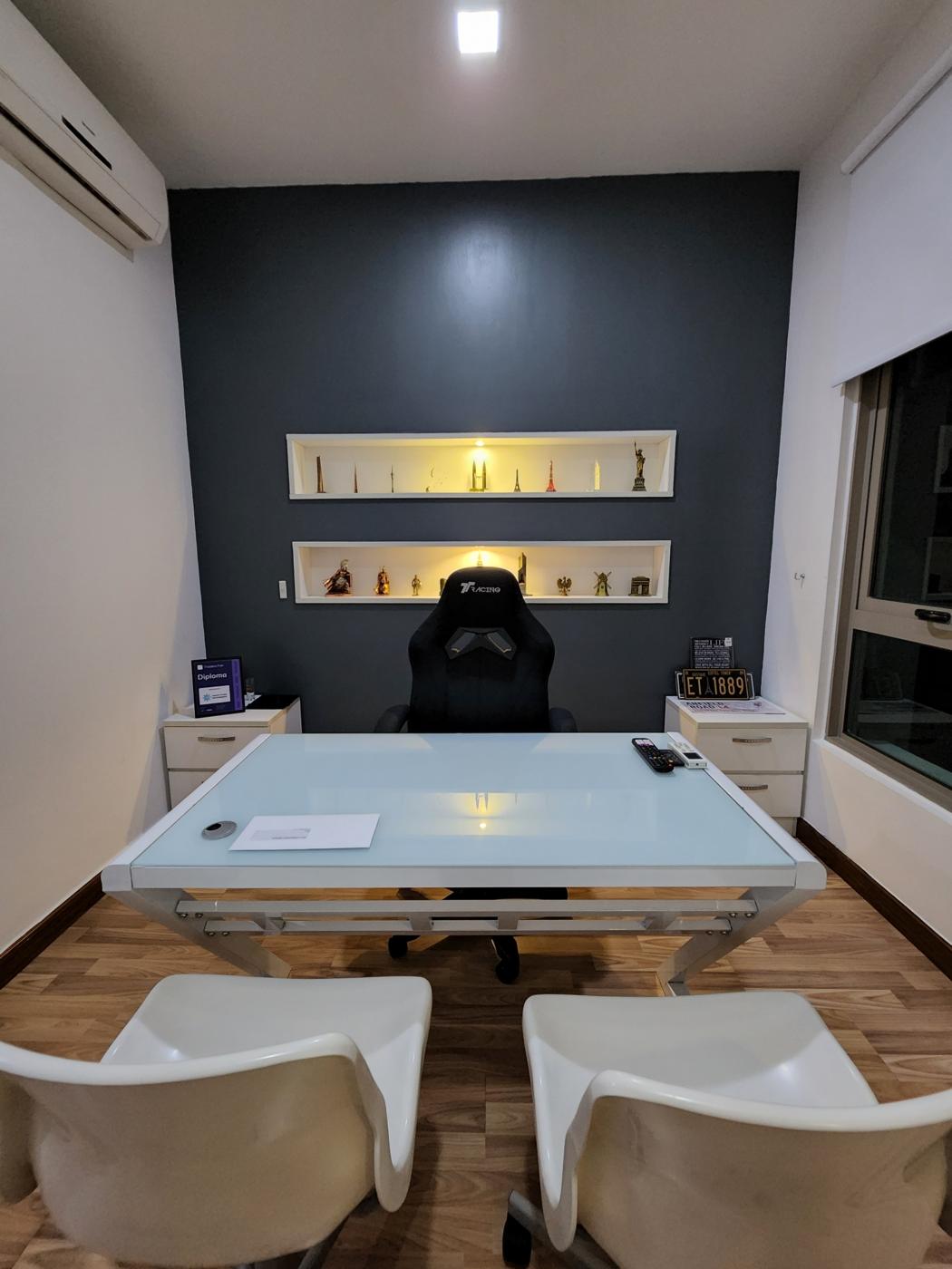 Work room seen from the entrance, with desk, two chairs and lit shelves