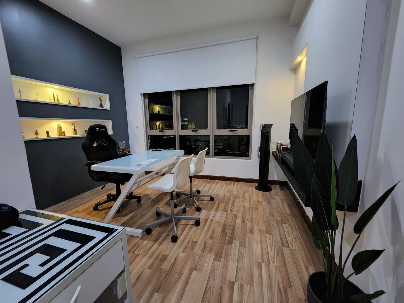 Wider view of the work room with desk, chairs, television and plant